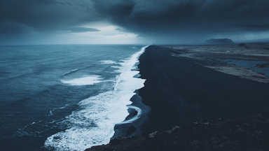 cached/dharmx_walls/cold/a_black_sand_beach_with_waves_and_clouds_above.jpg