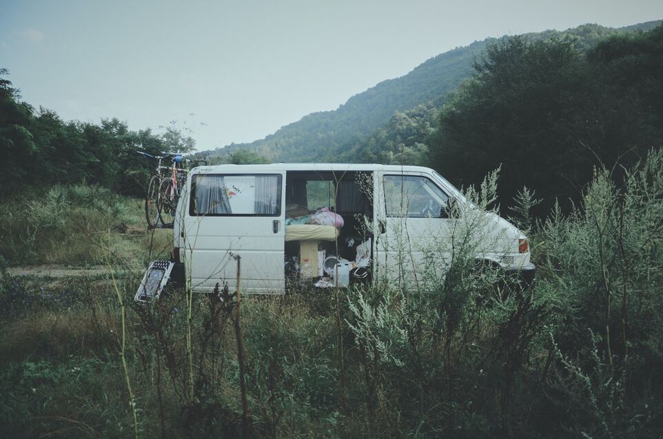 cached/dharmx_walls/decay/a_van_in_a_field_with_a_bicycle_and_a_mountain_in_the_background.jpg