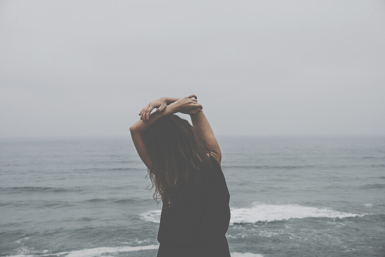 cached/dharmx_walls/girl/a_woman_standing_on_a_beach_with_her_hands_up.jpg