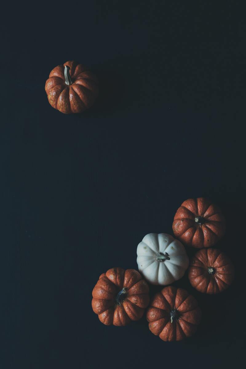 cached/dharmx_walls/halloween/a_group_of_pumpkins_on_a_black_surface.jpg