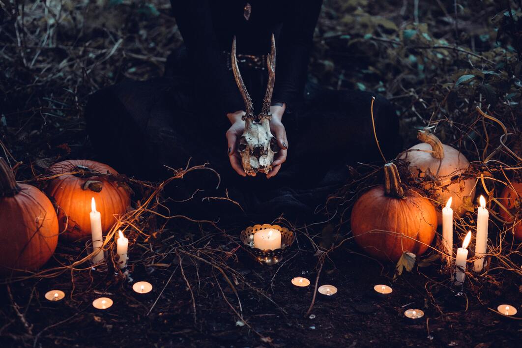 cached/dharmx_walls/halloween/a_person_holding_a_skull_and_pumpkins.jpg