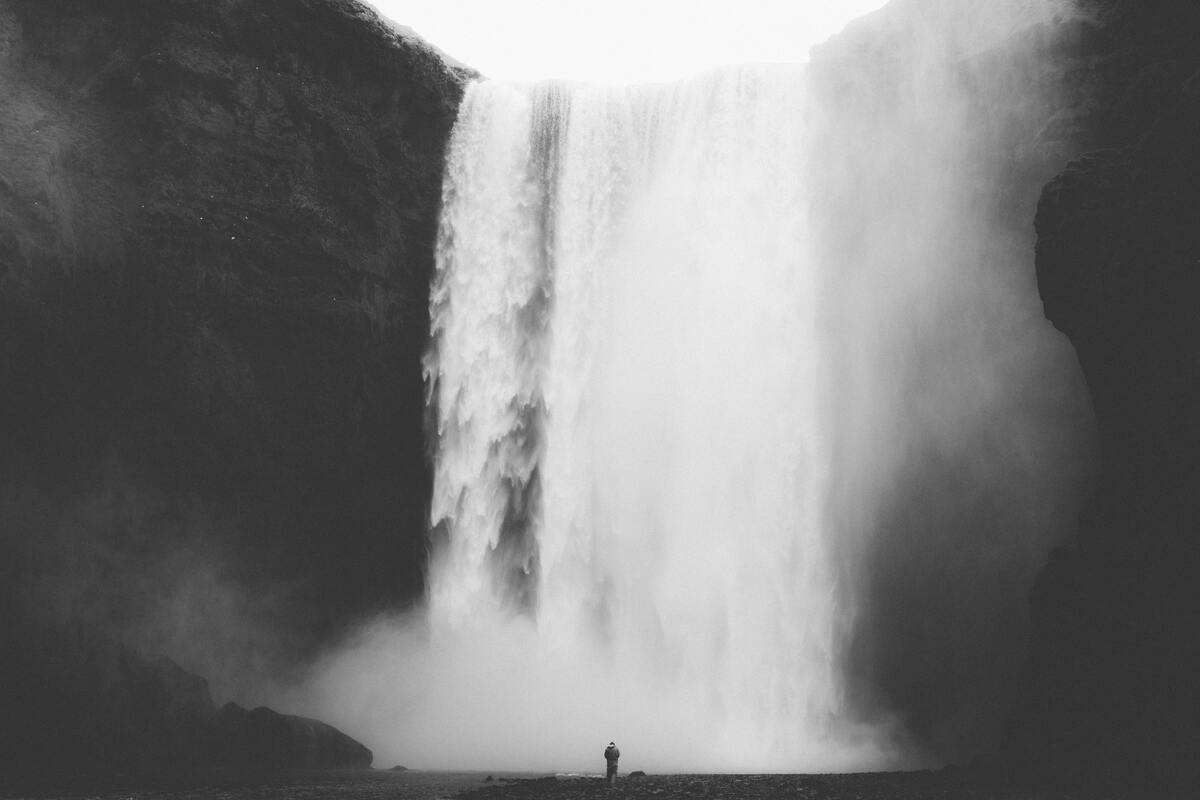 cached/dharmx_walls/monochrome/a_person_standing_in_front_of_a_waterfall.jpg