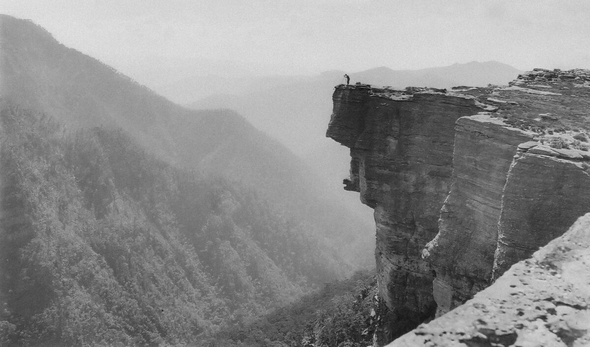 cached/dharmx_walls/monochrome/a_person_standing_on_a_cliff_edge.jpg