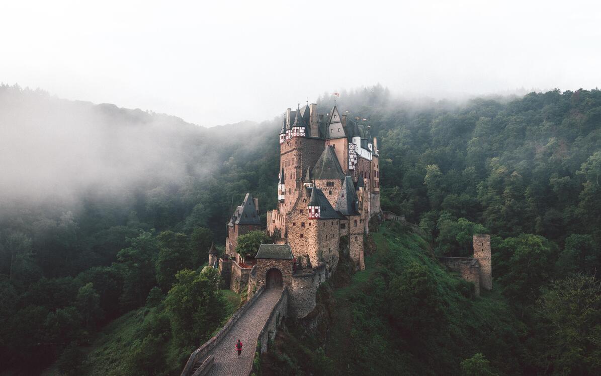cached/dharmx_walls/mountain/a_castle_on_a_hill_with_fog_with_Eltz_Castle_in_the_background.jpg