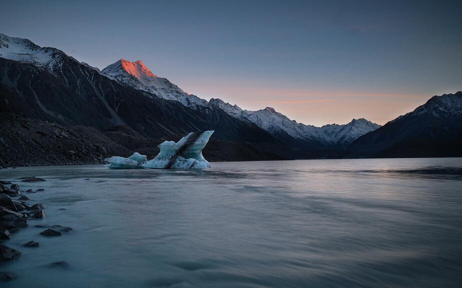 cached/dharmx_walls/mountain/a_iceberg_in_the_water_with_mountains_in_the_background.jpg