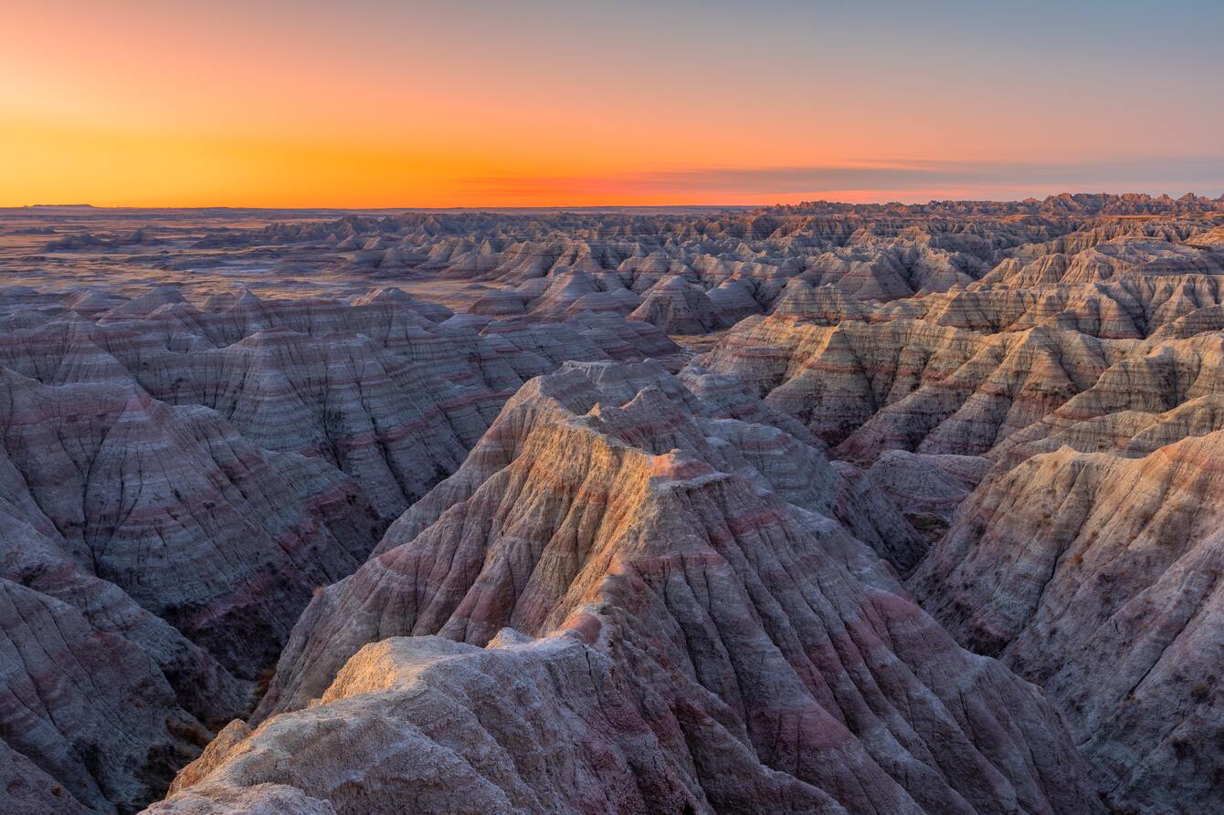 cached/dharmx_walls/mountain/a_large_canyon_with_a_sunset_with_Badlands_National_Park_in_the_background.jpg