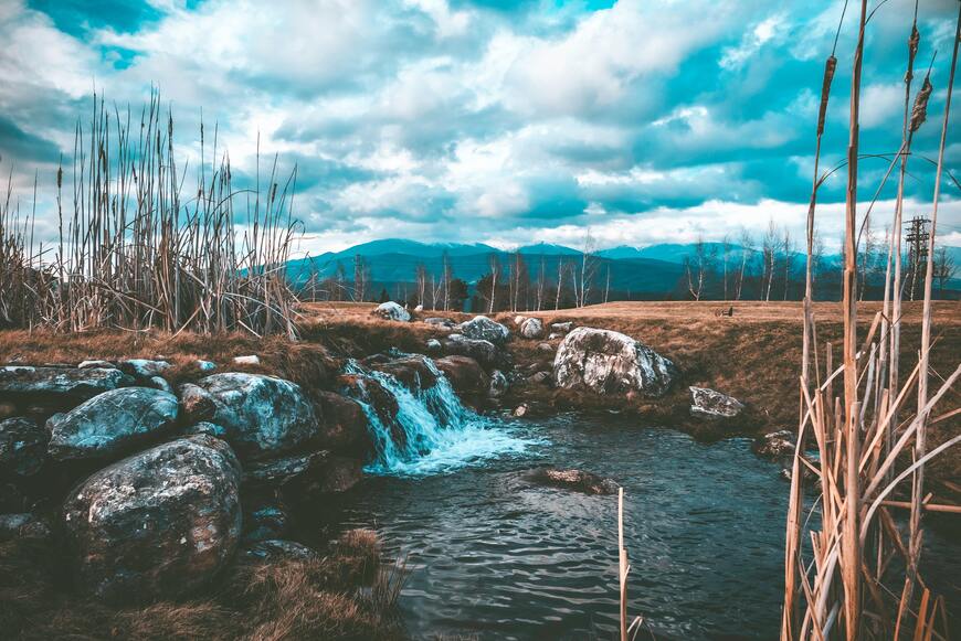 cached/dharmx_walls/mountain/a_small_waterfall_in_a_grassy_area.jpg