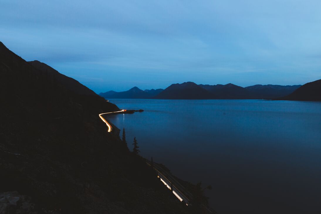 cached/dharmx_walls/nature/a_road_with_lights_on_the_side_of_a_body_of_water.jpg
