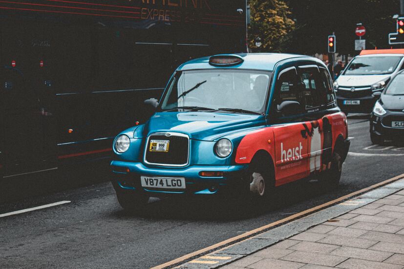 cached/dharmx_walls/unsorted/a_blue_and_red_taxi_on_the_street.jpg